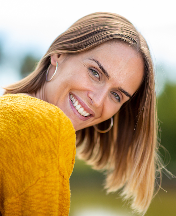 Smiling woman looking into mirror brushing her teeth smoothly